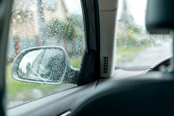 Fototapeta premium Side rear view mirror on a car. Reflection of rainy day at the car side mirrow.