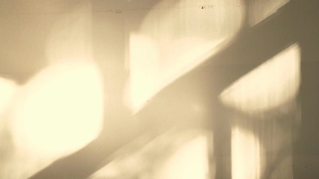The sun's rays are reflected on the wall. Bokeh from the sun's rays on the wall moving. Reflections on the walls move and create a pattern. Shadows on the walls from the sun form a beautiful ornament.