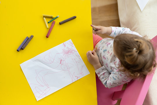 Toddler Girl Drawing With Crayons On Paper