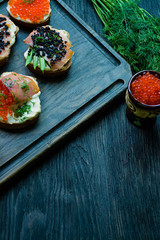 Sandwiches with red and black caviar. Close-up. Dark wooden background.