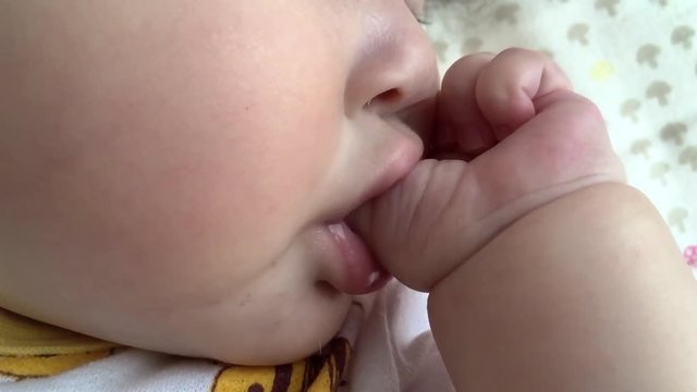 A female baby sucking a finger and sleeping