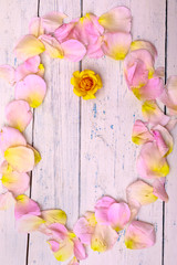 Frame from rose petals and beautiful orange rose on old rustic wooden table with copy space for text. Frame of flowers for Valentines Day. Top view of Summer background concept, flat lay. 