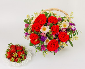 Fototapeta na wymiar basket with flowers and saucer with strawberries on white background