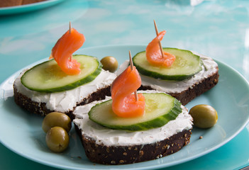 Sandwich with red fish, cucumber, cottage cheese and olives on a plate