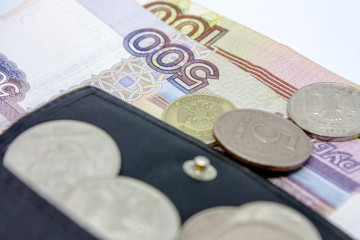 Russian paper money and a scattering of metal coins of different denominations on them a close-up on a black background.