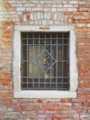 Old grated window in a brick wall in Venice city, Italy