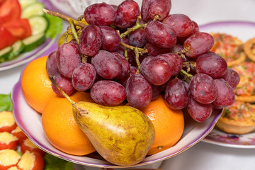 A bunch of grapes, pear and orange on the plate