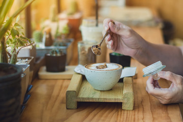 Woman pouring sugar into a white cup of coffee