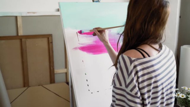 Artist writes on canvas. Gradient acrylic.Woman draws a gradient from blue to pink. Drawing with pink acrylic. Close up. Painting on canvas with acrylic. Repaints on top of the gradient color paint. 