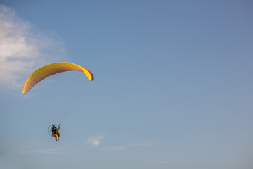 Adventure man active extreme sport pilot flying in sky with paramotor engine glider parachute. Paramotor flying on the sky at sunset. 