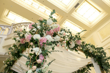Wedding chuppah decorated with fresh flowers indoor banquet hall of wedding ceremony. Luxury wedding florist decoration artwork