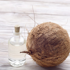 Coconut and oil in glass jar on white wooden table. Care concept