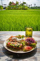 Healthy breakfast served on a vintage table with an emerald green rice field background. Concept of a healthy food and healthy lifestyle.
