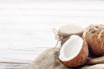 Coconut shell with meat on hemp sackcloth on white wooden kitchen table