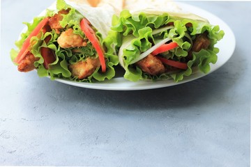 Doner kebab on a white plate. Shawarma with meat, onions, salad and tomato on on gray background. Eastern food.