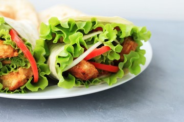 Doner kebab on a white plate. Shawarma with meat, onions, salad and tomato on on gray background. Eastern food.