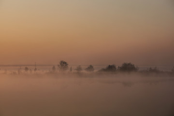 Foggy morning on the lake. Orange backlight.