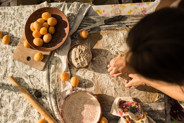 woman in gentle sundress cooking a sweet pie with fresh apricots on a sunny summer day