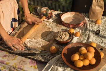 woman in gentle sundress cooking a sweet pie with fresh apricots on a sunny summer day