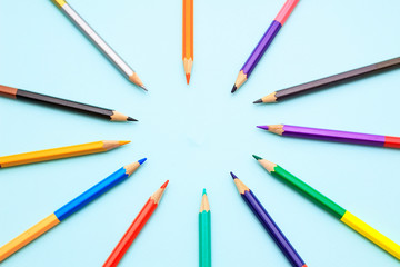 Color pencils in arrange in color wheel colors on blue background. Vie top. A free place for text.