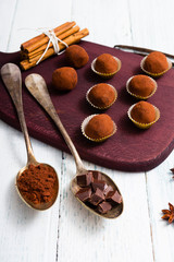 chocolate truffles, cocoa powder, broken dark chocolate on white wooden