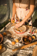 woman in gentle sundress cooking a sweet pie with fresh apricots on a sunny summer day