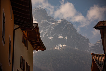 Houses with mountain views, Molveno, Trentino, Italy. Alpine landscape with clouds and snow.