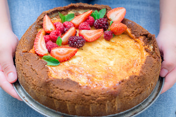 top view of woman holding cheesecake cake with berries 