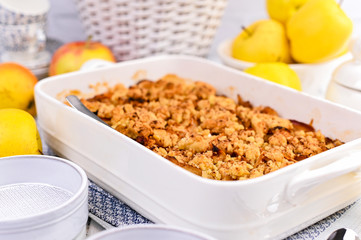 Apple pie in white ceramic baking dish. Homemade breakfast with apples and a la carte plates. Bright photo. Free space for text.