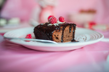 tasty homemade chocolate birthday cake decorated of some raspberries and candles served on the gentle pink background