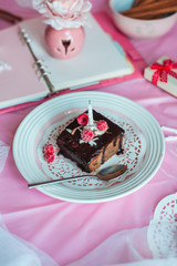 tasty homemade chocolate birthday cake decorated of some raspberries and candles served on the gentle pink background