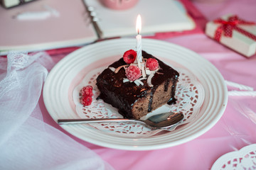 tasty homemade chocolate birthday cake decorated of some raspberries and candles served on the gentle pink background
