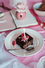 tasty homemade chocolate birthday cake decorated of some raspberries and candles served on the gentle pink background