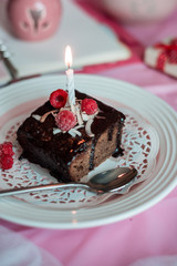 tasty homemade chocolate birthday cake decorated of some raspberries and candles served on the gentle pink background
