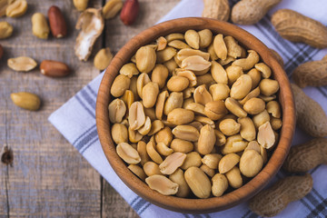 Peanuts in wooden bowl on natural wooden desk.