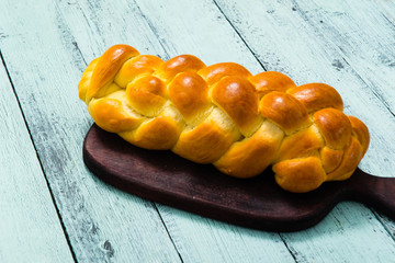 fresh challah bread on cutting board, blue wooden table