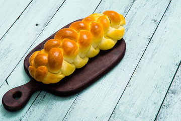 fresh challah bread on cutting board, blue wooden table