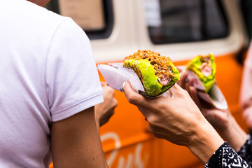 Hot dog in the hand, fast unhealthy food on the street