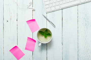 work place with cup of mint tea, pink post its and pen, directly above