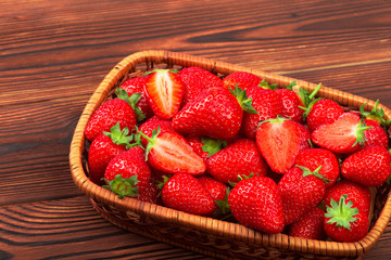 Juicy washed strawberries in wooden bowl on kitchen table.