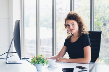 Young attractive business woman smiling while sitting in office desk