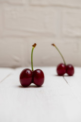 Close up ugly organic cherries on white wooden background, selective focus