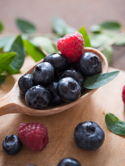 blueberry and raspberry on the wooden spoon macro
