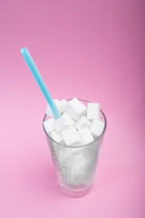 Full glass of refined sugar on a pink background. concept sugar in the code. Copy space for text.