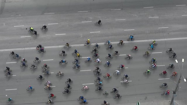 Many cyclists ride along the road. Bike ride on the street shot from above aerial view.