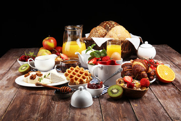 Huge healthy breakfast on table with coffee, orange juice, fruits, waffles and croissants. Good morning concept.