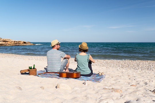 Couple with a guitar having fun on a mediterranean beach. Summer holidays
