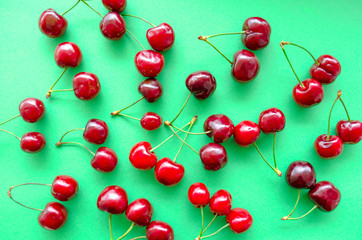Bright juicy berries of a sweet cherry lie on a green table in a free order. Top view, background, flat lay, selective focus image.