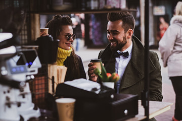 Attractive smart couple is enjoying coffee while sitting outside at small coffeeshop