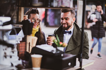 Attractive smart couple is enjoying coffee while sitting outside at small coffeeshop